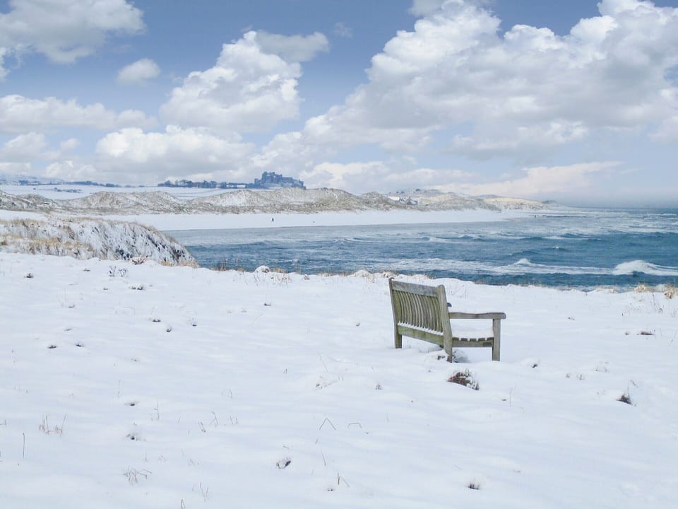 Bamburgh Castle sits proudly above the snow-covered dunes and beaches | Spindrift, Seahouses