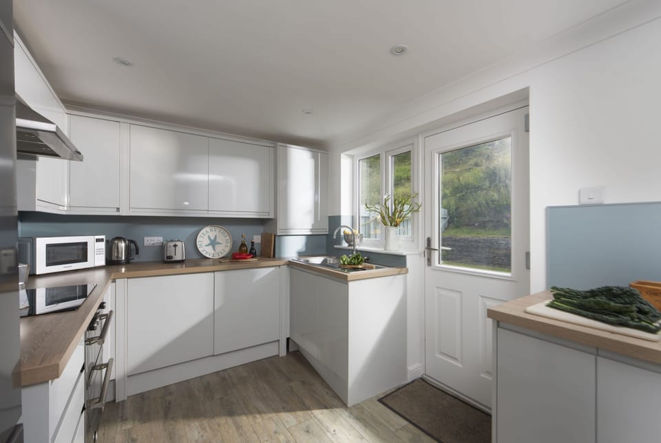 Castaways, Porthtowan. Ground Floor: The kitchen is well equipped with an electric oven and hob, microwave, fridge/freezer, dishwasher and washer/dryer