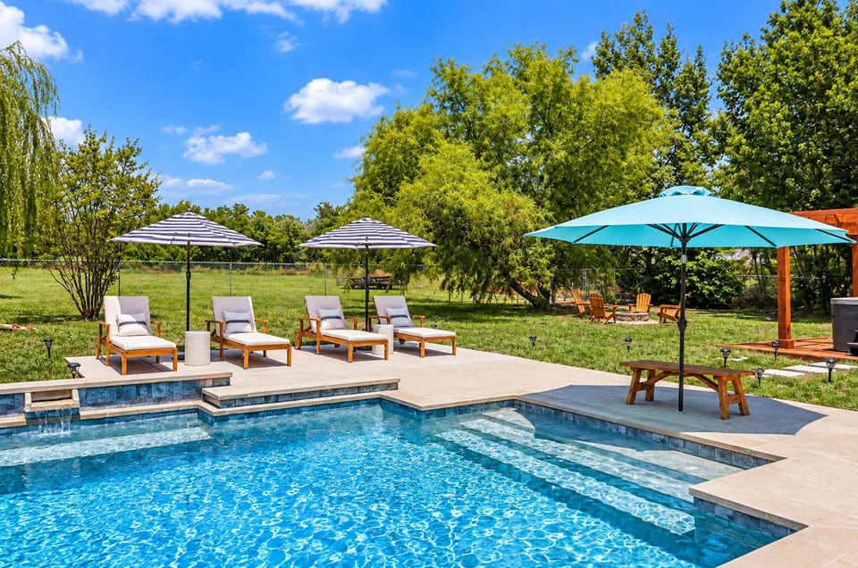 Sunny pool area with lounge chairs and umbrellas.