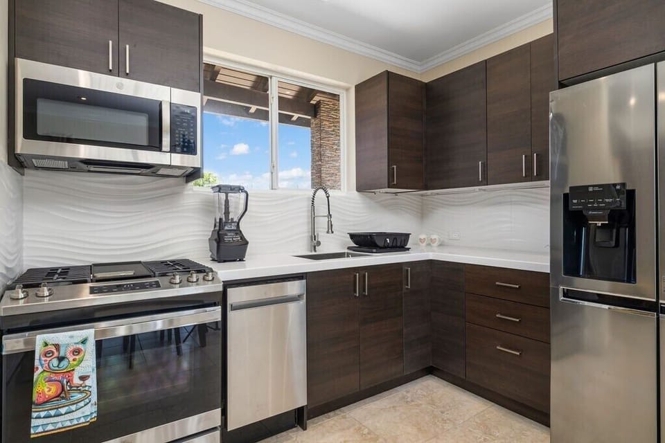 Fully equipped kitchen with modern appliances including a microwave, refrigerator, stove, oven, coffee maker, dishwasher, and all the dishes and utensils needed for easy meal prep.