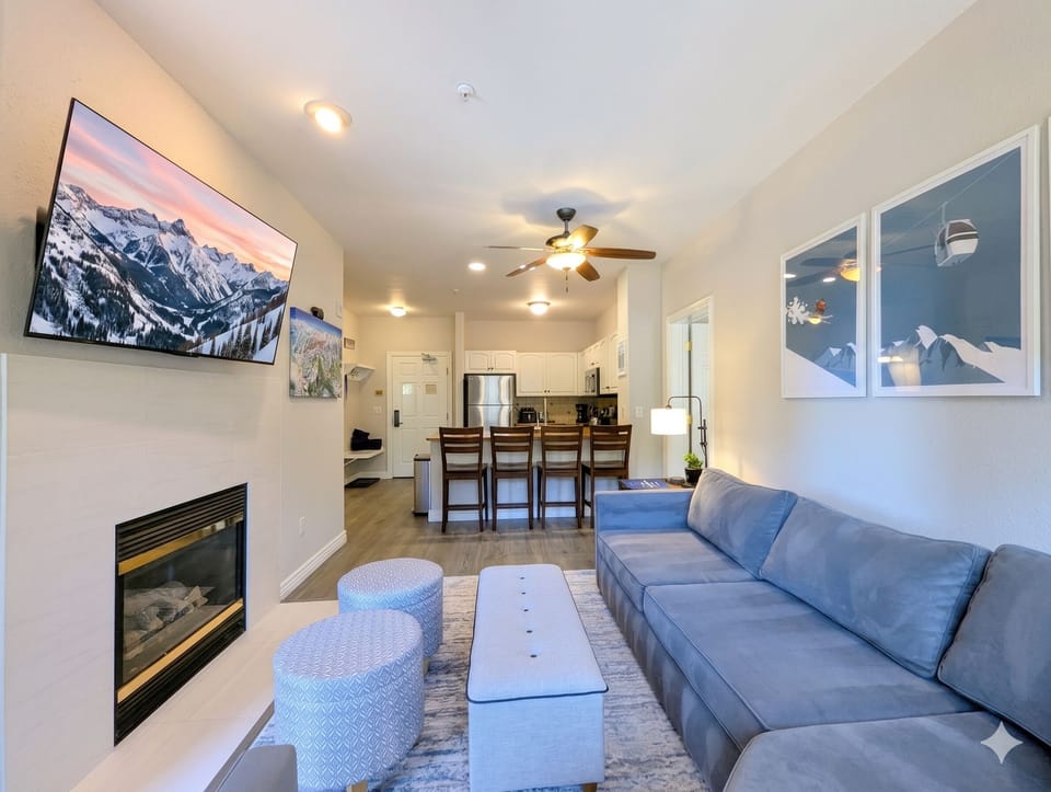 Settle into this bright, open living space where comfort meets alpine style. Relax by the fireplace, unwind on the plush sofa, and enjoy mountain views from your screen and walls.