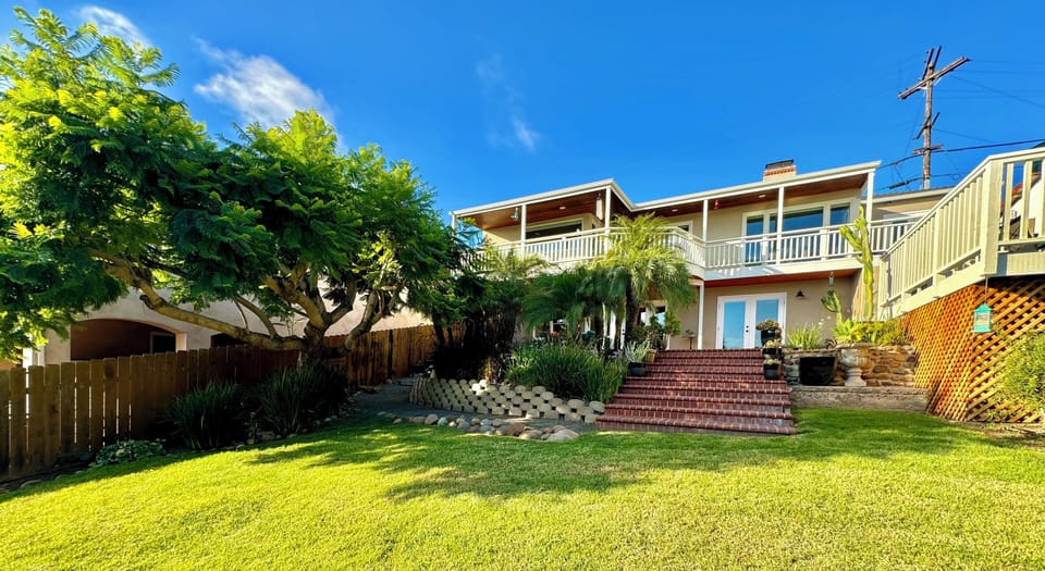 Fenced backyard with large lawn, cornhole and lawn bocci