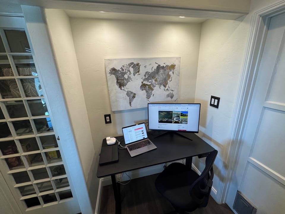 Dedicated workspace off kitchen, standup desk, chair, and monitor.