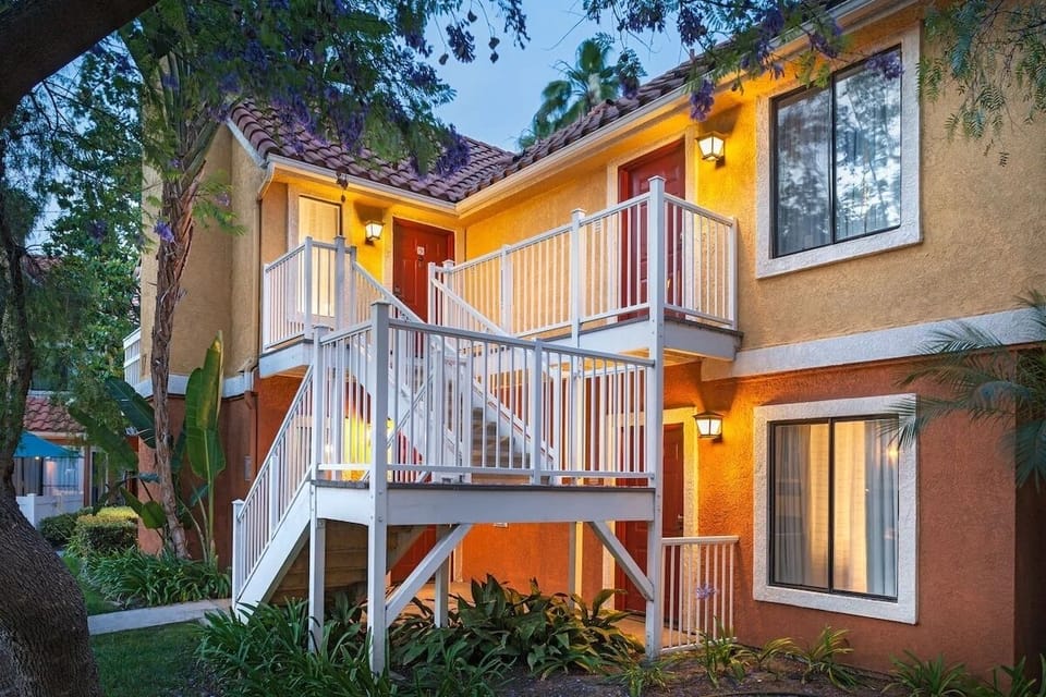 Arrive to a warmly lit entrance framed by lush greenery.