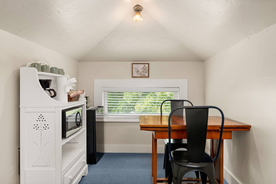 Charming nook with a small dining table for two, mini fridge, microwave, and coffee station.