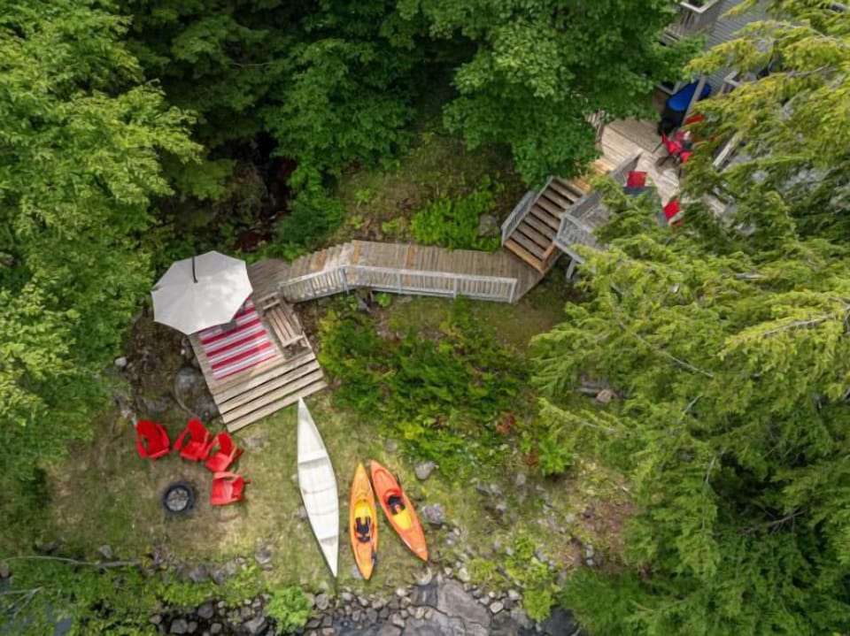 Aerial view of lakefront with deck, kayaks, and dock. Your escape awaits!