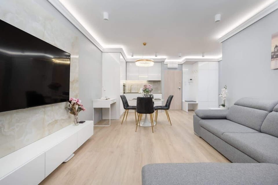A modern open-plan living room and kitchen with soft lighting and sleek decor.
