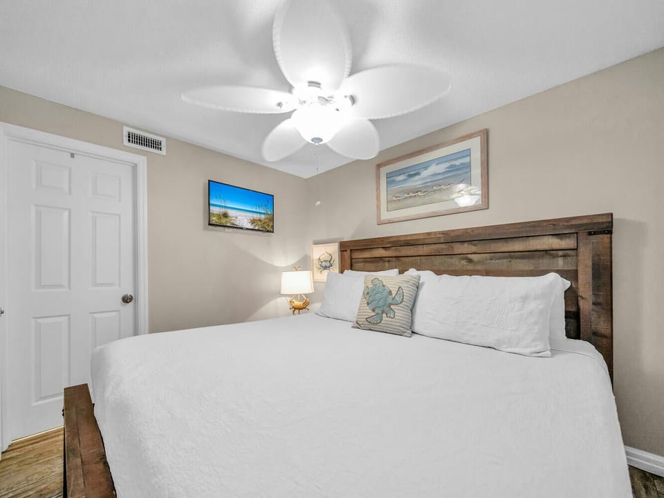 Rest peacefully in your coastal-themed bedroom with rustic wood headboard, crisp linens, and gentle ceiling fan breeze.