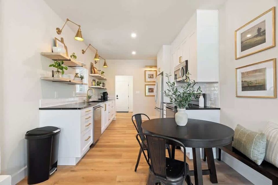 The galley-style kitchen, features beautiful lighting that illuminates the space. Open shelves add a stylish touch and provide easy access to essentials. Adjacent to the kitchen, a cozy dining area comfortably seats four people.