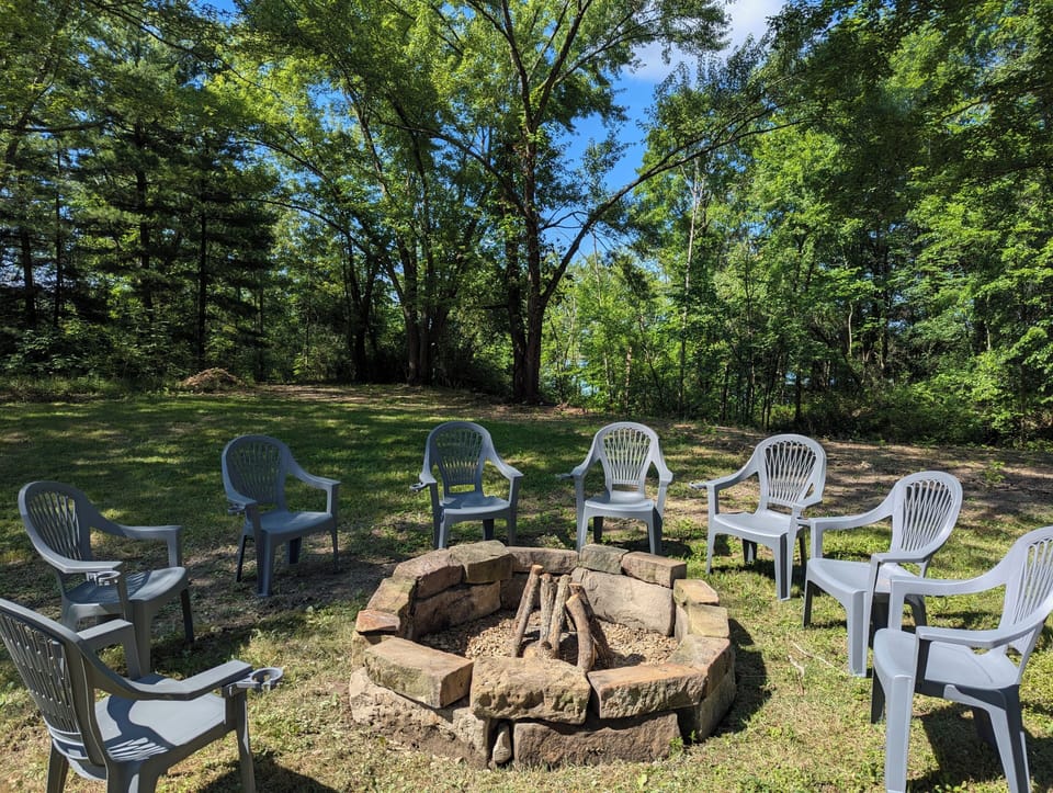 A view of the firepit. Views of the lake are seen between the trees