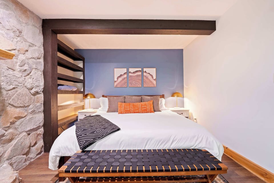 This stylish king bedroom blends rustic charm with modern comfort. Cozy up with soft linens, warm lighting, and built-in shelving for convenience. The perfect space to relax after a day of exploring.