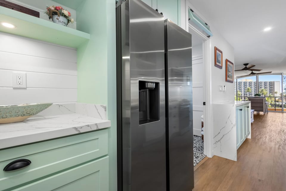 Your beautifully appointed kitchen features sleek stainless appliances and elegant marble countertops, bathed in natural light and designed for comfortable coastal living.