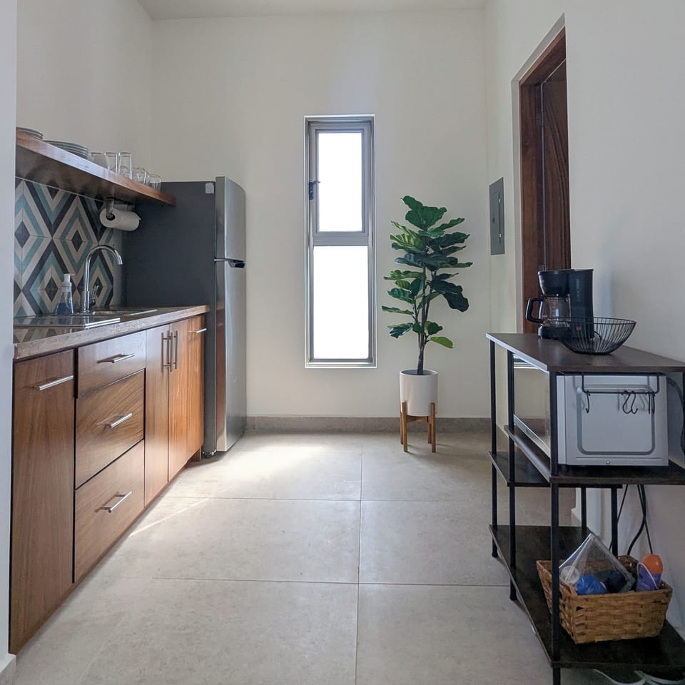 Kitchenette with refrigerator, cooktop, microwave, coffee maker, and cookware.