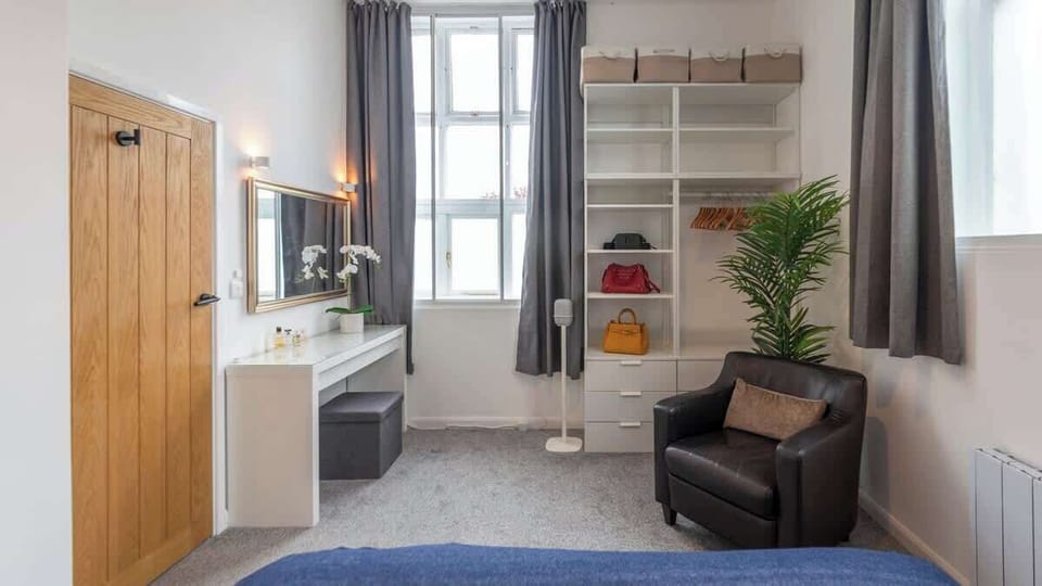 Spacious and serene — Bedroom 1 features a king-size bed, modern décor, ample storage, and cozy seating, all bathed in natural light for a truly restful retreat.