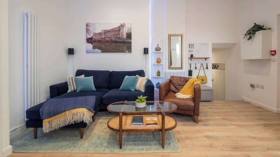 Warm, stylish, and inviting — this beautifully designed living room features a cozy navy sectional, a chic leather armchair, and a smart layout perfect for relaxing or entertaining in comfort and style.