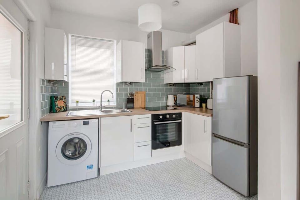 Minimalist and spotless — a clean kitchen area with sleek essentials and a convenient washing machine for a fuss-free stay.