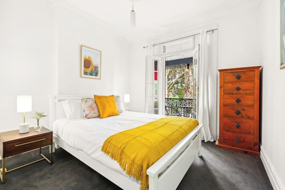 The primary bedroom is set upstairs with a plush queen-sized bed and opens to a quaint balcony. Please note, this bedroom does not have air conditioning. However, portable fans and heaters are provided for your comfort.

