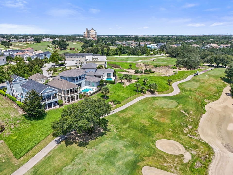 Aerial view showcasing the home’s location alongside a scenic golf course, with peaceful green views and surrounding res