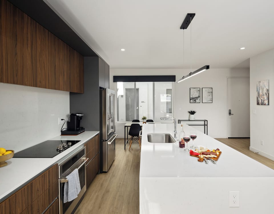 1st Floor: Fully equipped modern kitchen featuring culinary essentials, stainless steel appliances, island bar seating, and a dining area.