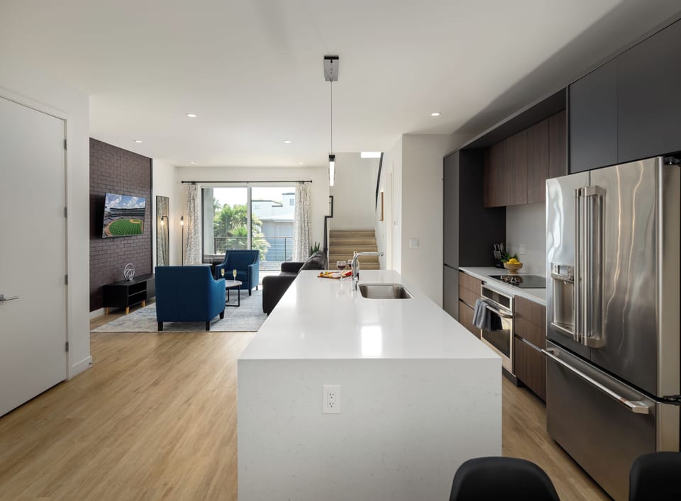 1st Floor: Fully equipped modern kitchen featuring culinary essentials, stainless steel appliances, island bar seating, and a dining area.