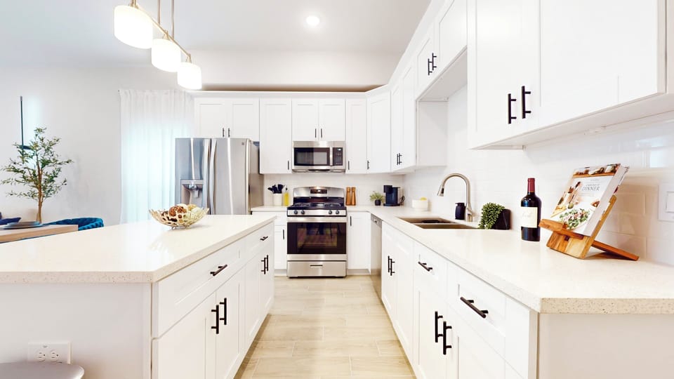 Modern kitchen featuring a stove, fridge, stove,  and microwave. 