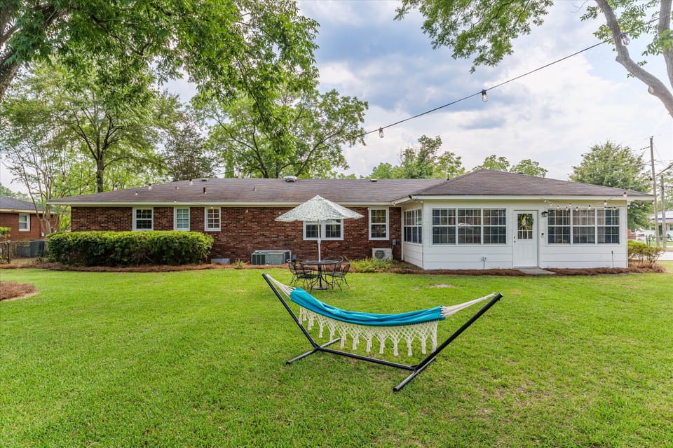 Fenced backyard with hammock, outdoor seating and lights. 