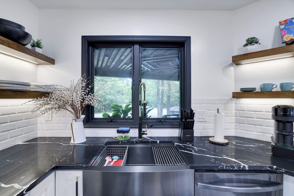 Sleek kitchen sink with black marble, wood shelves, and modern black fixtures.
