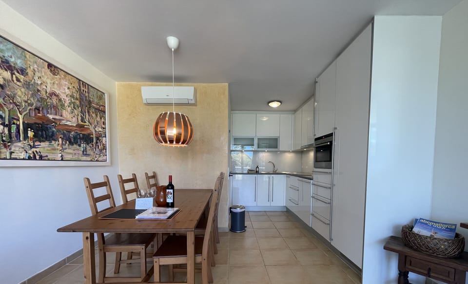 Dining area with wooden table next to a modern, fully equipped kitchen and cozy décor.