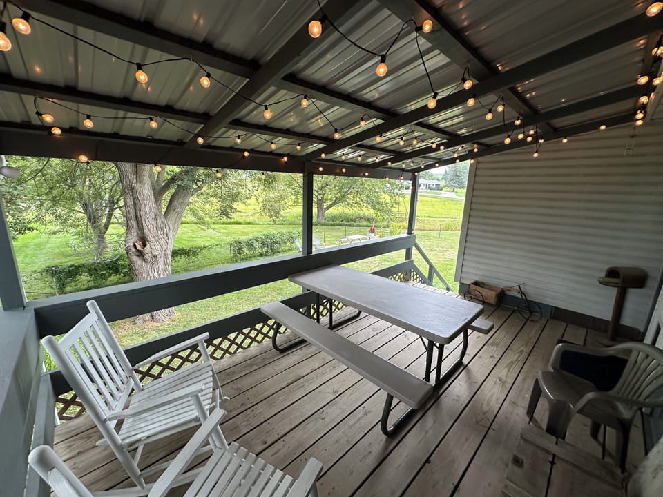 The covered deck includes ample seating plus a picnic table and string lights.