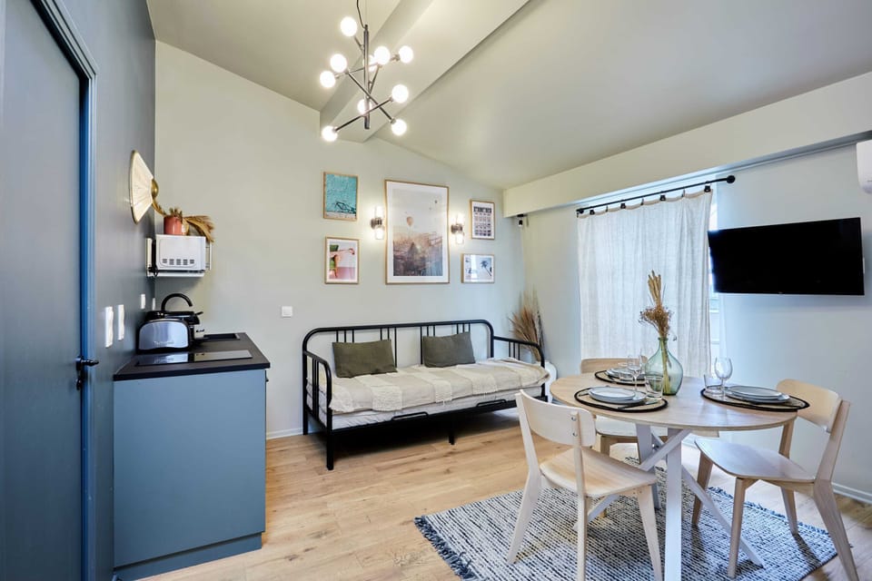 Grand studio avec lit double, un canapé lit simple, TV, coin repas et cuisine ouverte équipée.