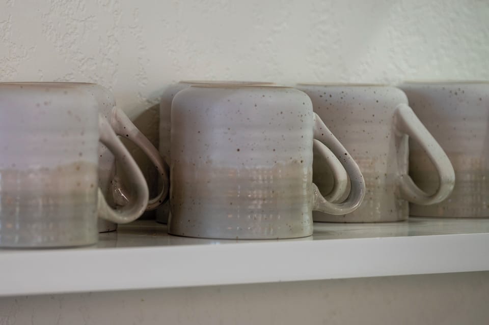 - Handmade style ceramic mugs add charm to your morning routine or evening tea - Neatly stacked on floating shelves for easy access during your stay - Each one has a rustic touch that complements the cozy cabin aesthetic