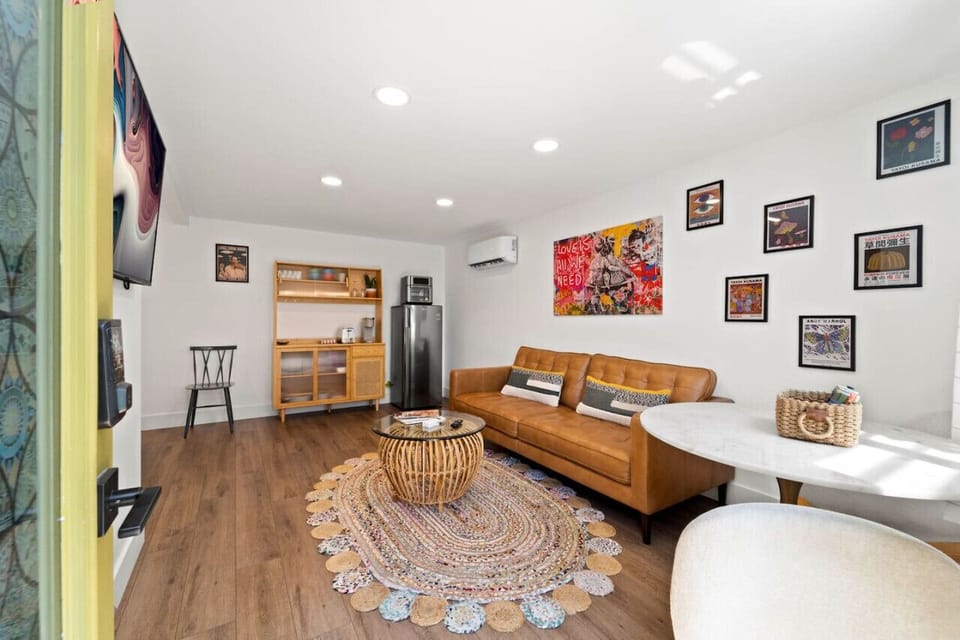 Cozy living room w/ leather sofa, wood coffee table & playful wall art that adds warmth and character.