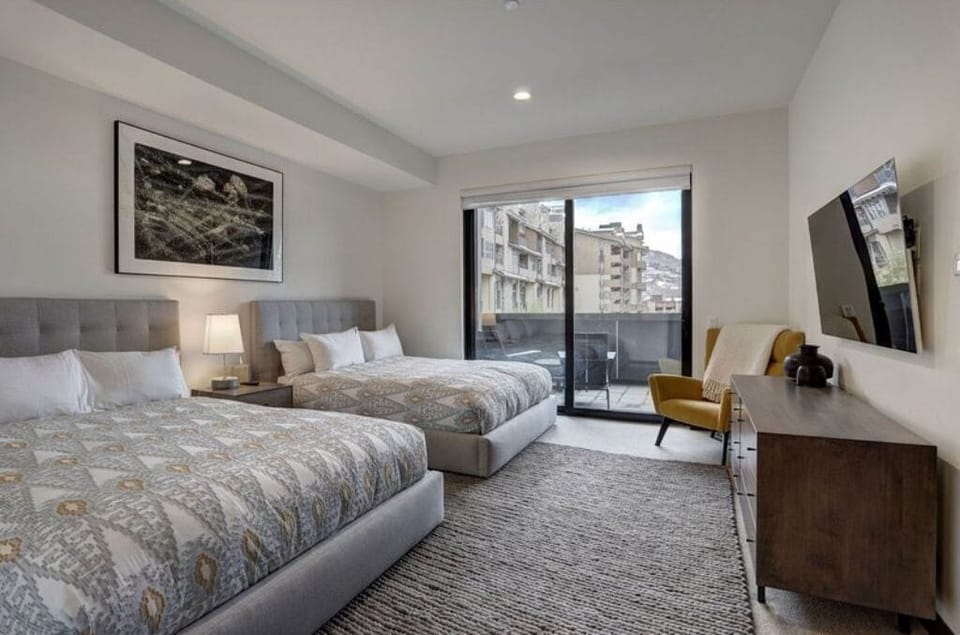 Elegant bedroom featuring two plush beds and a flat-screen TV.