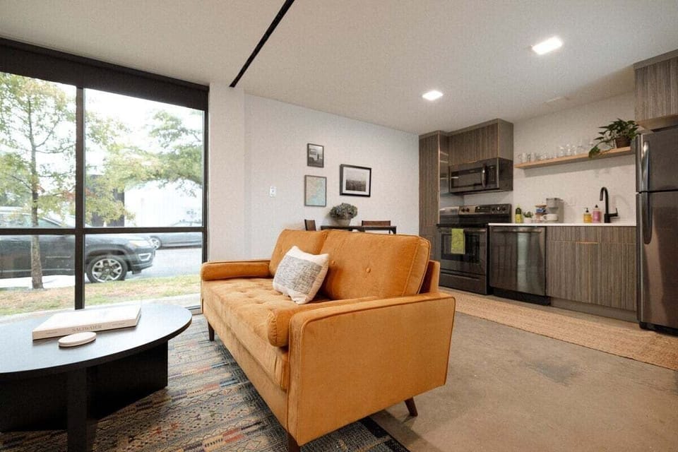 Relax downstairs in a bright, thoughtfully designed living space featuring comfortable seating, a Smart TV for streaming, and fast 500mbs AT&T Fiber Wi-Fi