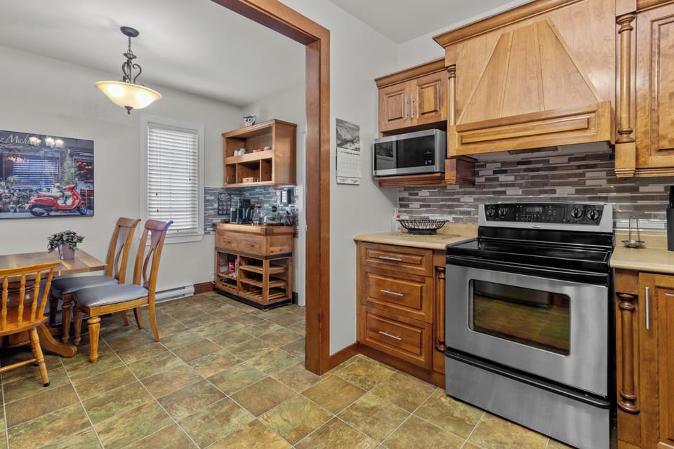 The dining area, adjacent to the kitchen, features a stylish table and chairs, perfect for family meals. The kitchen itself is equipped with modern appliances, beautiful wooden cabinetry, and a chic tile backsplash.