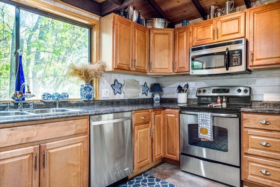 Closer kitchen view showing the sink, dishwasher, range, microwave, counters, and cabinetry.