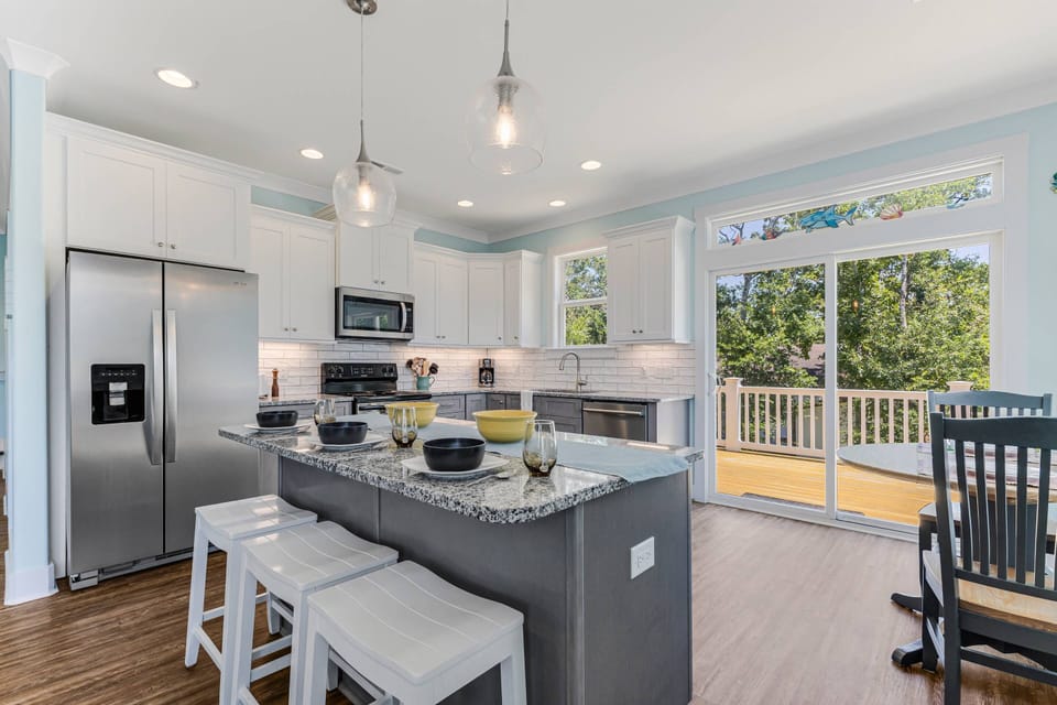 The kitchen features a breakfast bar for 3 and a dining table for 2 with a view of the porch, comfortable and inviting space for meals.
