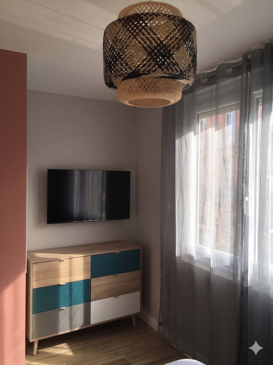 Détail du coin multimédia avec écran plat, rangements et plafonnier en osier