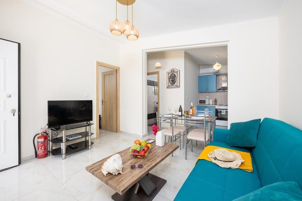 Open-plan living room with sofa, dining area, kitchen, A/C, WiFi internet, and satellite TV