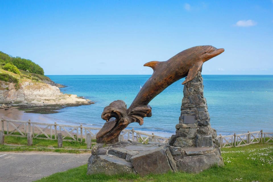Wooden carving of a dolphin overlooking the beach