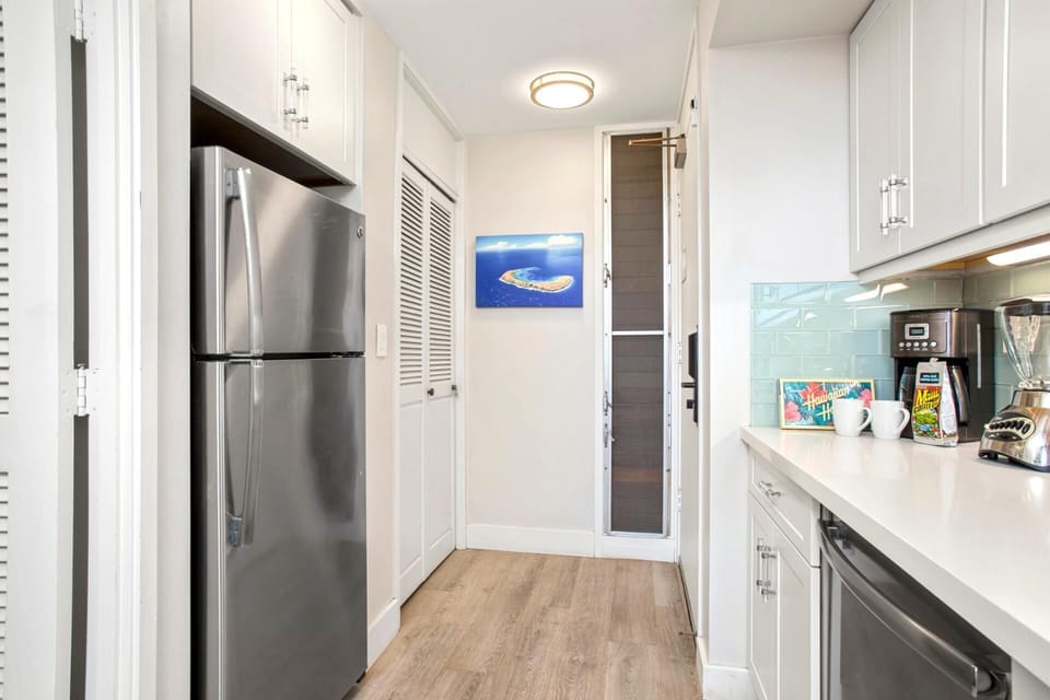 Whip up magic in this soft-toned galley with minty backsplash, sleek counters, and a wink of tropical flair    