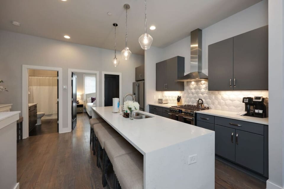 Spacious kitchen featuring dark cabinetry, a long island, coffeemaker, and stylish pendant lights