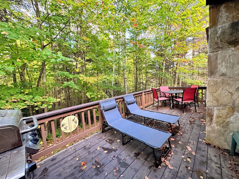 Main level deck has a patio table, loungers and a gas grill