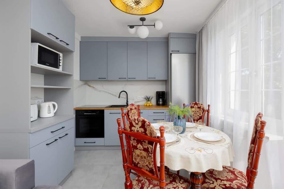 A small dining area connected to a modern kitchen. Elegant red chairs and white walls create a stylish atmosphere.