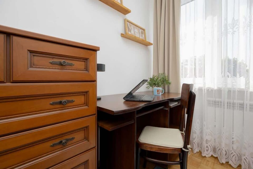 A traditional-style bedroom with a desk, drawers, and wooden accents. Ideal for work or study at home.
