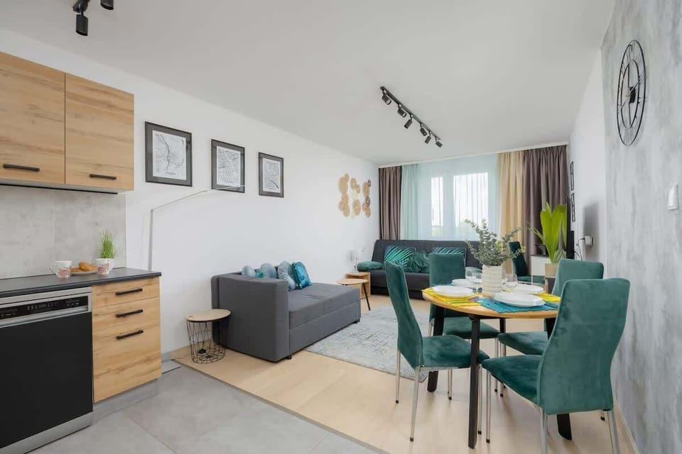 A dining and kitchen area featuring wooden cabinets and a small table with elegant green chairs. Bright and functional space for meals and socializing.