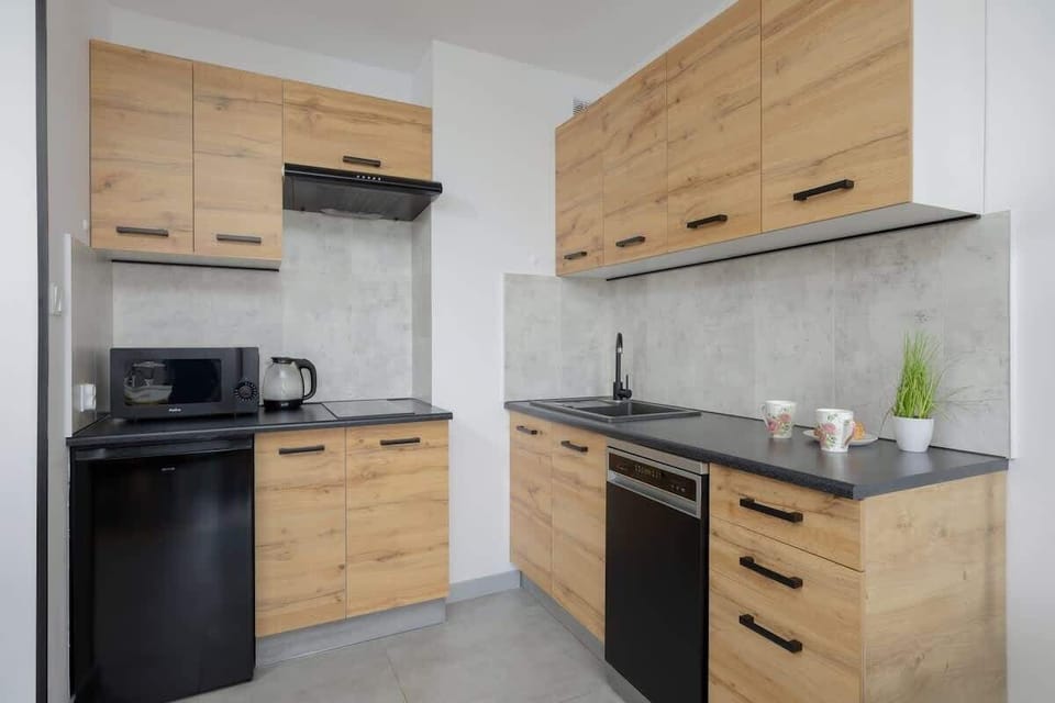 A sleek kitchen with wood-finish cabinets and black appliances. Compact yet fully equipped for everyday cooking needs.