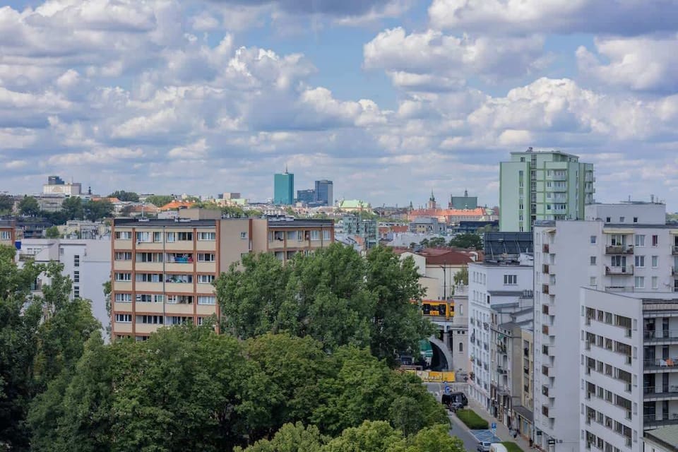 A panoramic view of residential rooftops and leafy surroundings. The large windows let in plenty of natural light.