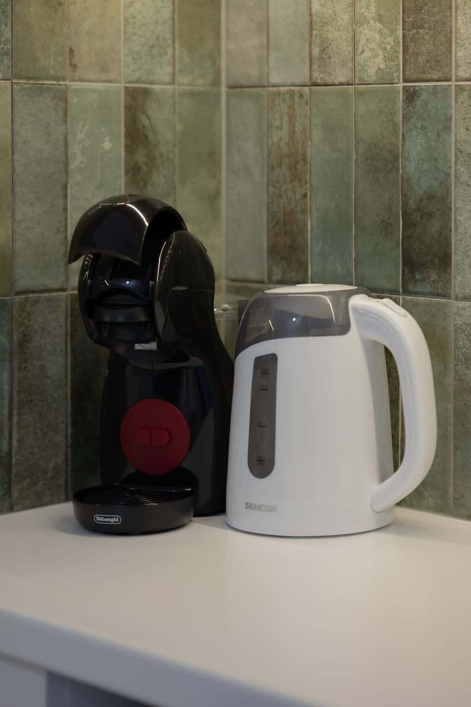 A close-up of a small counter with a coffee machine and electric kettle. Ideal for preparing quick drinks in the morning.
