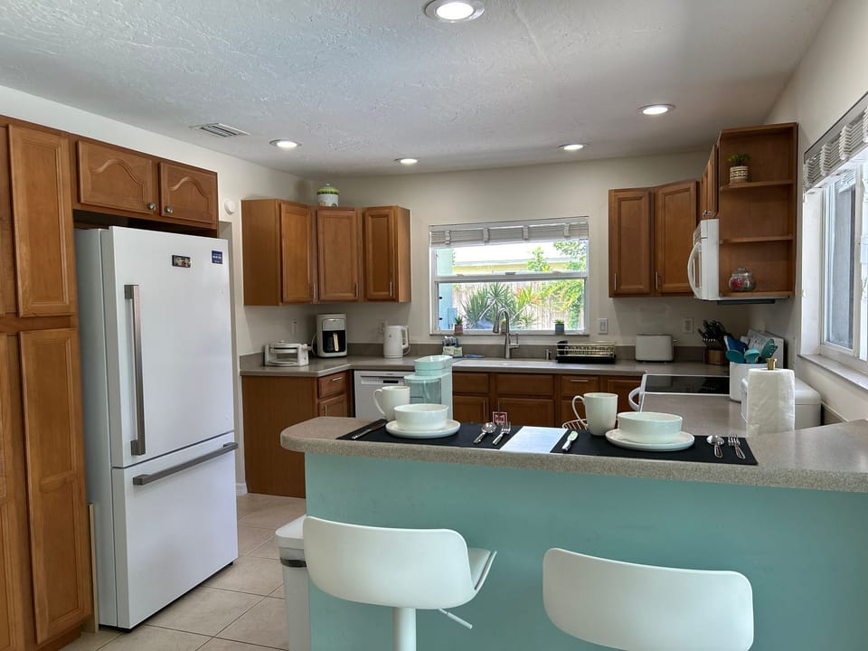 Fully-equipped kitchen w/ breakfast bar w/ 2 bar stools and direct pool access.